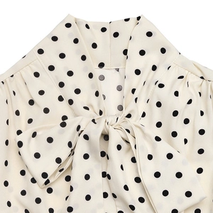Détail du col à nœud papillon et pois noirs sur tissu en mousseline beige clair