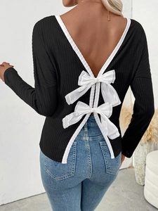 Detail of sexy backless long sleeve top with white bows and black ribbed texture fabric