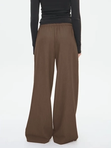 Detail view of brown wide-leg casual pants with elastic waistband and draped fabric texture