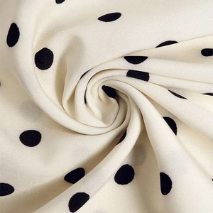 Détail macro du tissu à pois soyeux montrant la texture douce et le drapé fluide de la robe