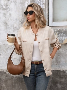 Détail de la veste en maille beige texturée avec boutons dorés vintage et col côtelé