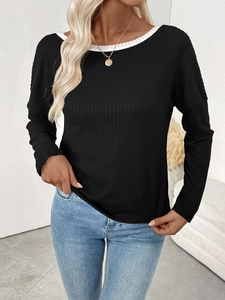 Close-up of black ribbed knit sweater featuring a white contrast trim round neckline