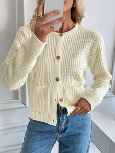 Detail shot of the cream knit cardigan showing textured fabric and embossed gold buttons