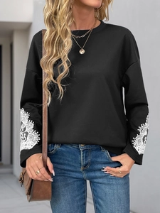 Detail view of women's black sweatshirt featuring white lace mandala patterns on sleeve cuffs