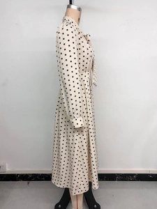 Détail d'une robe beige à pois avec manches longues et une ceinture nouée à la taille