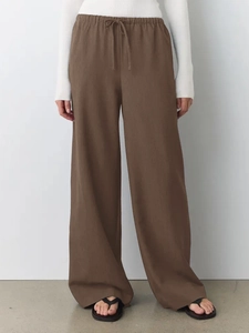 Detail of dark brown wide-leg trousers featuring elastic drawstring waist and textured fabric