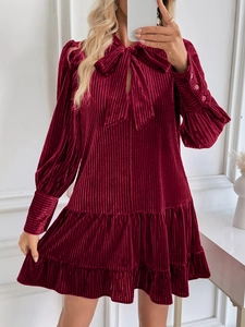 Détail de la robe en velours bordeaux avec col à nœud et texture à volants
