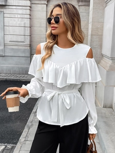 Detail of white cold-shoulder blouse with elegant ruffles and tie-waist detail