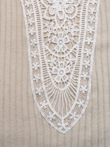 Vue détaillée du tricot côtelé sable avec une application de dentelle florale blanche fine