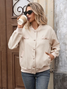 Détail de la veste élégante en tweed beige avec tissu texturé et boutons dorés
