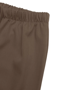 Detail of wide elastic waistband and twill texture on dark brown casual trousers