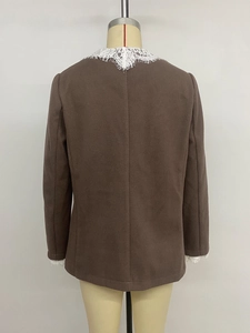 Dettaglio del pizzo bianco sullo scollo di una giacca blazer marrone scuro da donna