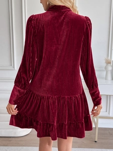 Détail de la robe en velours bordeaux avec texture côtelée et ourlet à volants élégant