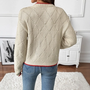 Women's cream knit sweater with red scalloped edges and diamond pattern in home setting