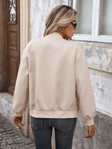 Vue détaillée de la texture du blouson bomber en tweed beige et des poignets côtelés