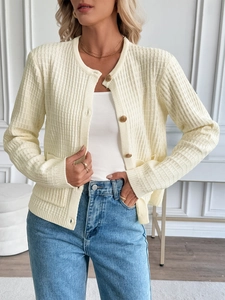 Close-up of golden embossed buttons and ribbed texture on yellow knit cardigan