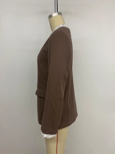 Dettaglio del blazer con bordi in pizzo bianco su colletto e polsini in tessuto a trama