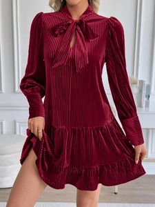 Détail de la robe en velours bordeaux avec col à nœud et ourlet à volants superposés