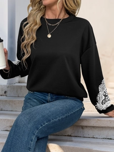 Close-up of white lace embroidery details on black sweatshirt cuffs with a high texture