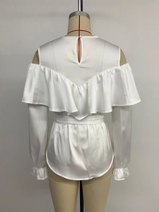 Detail of white satin cold-shoulder top showing elegant ruffle layers and silky texture