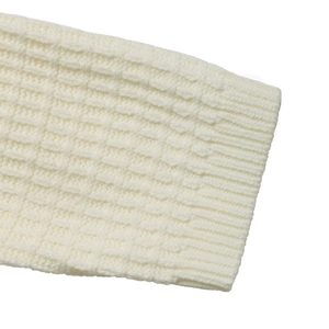 Detailed close-up of white waffle knit sweater fabric with rib-knit cuff finish