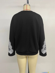 Detail view of the back of a black crewneck sweatshirt with lace patterns on sleeves
