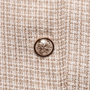 Détail du tissu en tweed avec un bouton en métal doré au motif de couronne
