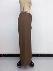 Detailed side view of dark brown wide-leg pants featuring an elastic drawstring waistband