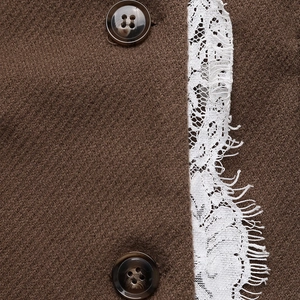Dettaglio di bottoni a tartaruga e pizzo bianco su una giacca blazer di lana marrone