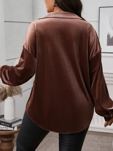 Detail of loose-fit brown velvet shirt showing smooth fabric texture and draped back hem
