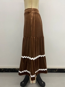 Détail de la jupe longue en velours marron à volants avec dentelle blanche ondulée