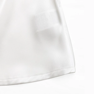 Detailed close-up of pure white blouse hem featuring precision double-needle stitching