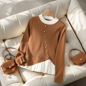 Detail of color-block knit sweater with golden buttons and pleated white hem design