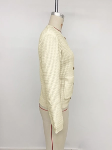 Detail of cream knit cardigan featuring gold buttons and waffle textured fabric