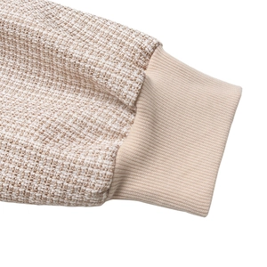 Détail du tissu en tweed et des poignets en tricot côtelé sur veste femme