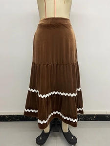 Détail d'une jupe mi-longue en velours marron avec des volants et de la dentelle blanche