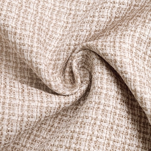 Gros plan sur la texture tissée du tweed beige de cette veste à col baseball chic