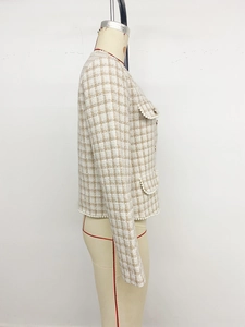 Detail view of woven tweed texture and elegant pearl trim on a beige checkered jacket