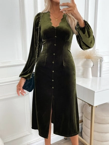 Détail d'une robe midi élégante en velours vert foncé avec col en V et boutons décoratifs