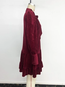 Détail de la robe en velours bordeaux à plis verticaux et ourlet à volants superposés