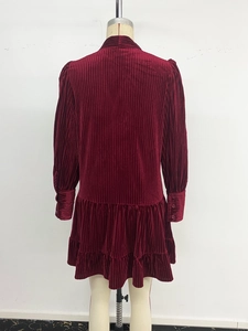 Détail d'une robe en velours bordeaux avec volants superposés et tissu texturé rayé
