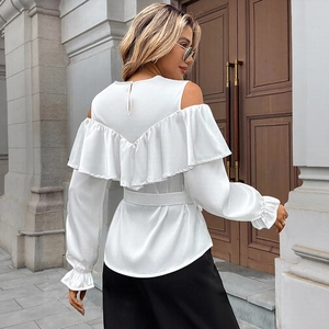 Elegant white cold-shoulder blouse with ruffles and waist tie on a street model