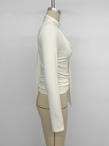 Detail view showing draped cowl neck and fitted long sleeve on white pleated top
