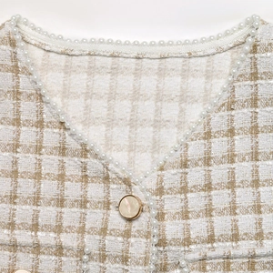 Detailed macro view of tweed cardigan neckline with pearl trim and elegant button