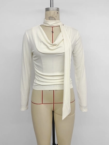 Detail of elegant white long sleeve top featuring a draped cowl neck and hanging ribbon ties