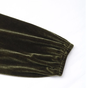 Vue macro des poignets d'une robe en velours vert olive avec design plissé élastique