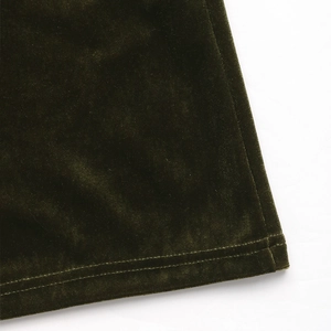 Détail de l'ourlet d'une robe en velours vert foncé avec une double couture précise