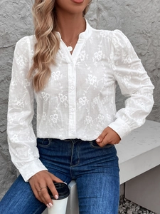 Détail du chemisier blanc à manches longues avec broderie florale et col montant élégant