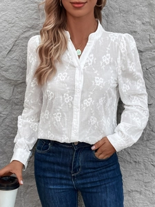 Détail de broderie florale blanche et manches bouffantes sur chemisier en dentelle