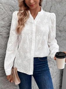 Détail de la chemise blanche à manches longues avec broderie florale et manches bouffantes